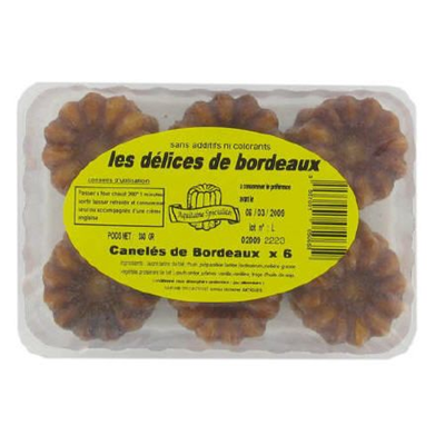 Pack of six Les Délices de Bordeaux Canelés in a clear plastic tray with a yellow label, showcasing the traditional French pastries with caramelised crusts and fluted shapes. The label highlights the artisanal recipe and absence of additives or colourants.
