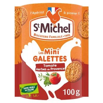 Packaging of Saint Michel Mini Galettes Tomate Herbes de Provence 100g, showing round savoury biscuits, a tomato with herbs, and the St Michel logo inside a white chicken silhouette on a red-orange background. Features “sans huile de palme” (no palm oil).
